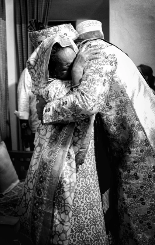 a couple of people that are hugging each other, a black and white photo, by Miroslava Sviridova, hurufiyya, embroidered brocade robes, his last moment, 15081959 21121991 01012000 4k, father
