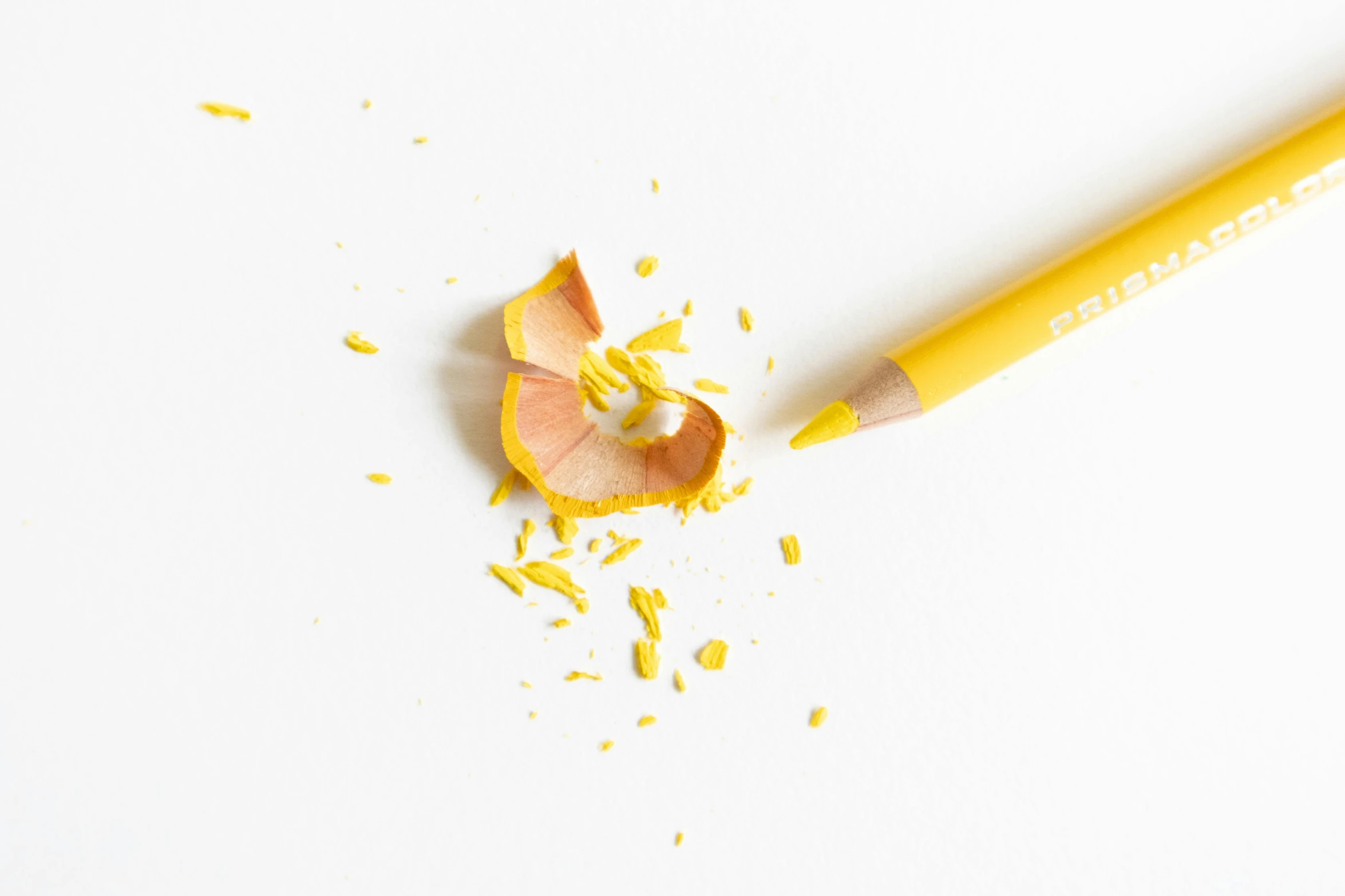 a pencil and shavings on a white surface, by Gavin Hamilton, pexels, hyperrealism, with lemon skin texture, yellow flash, professional product photo, orange yellow