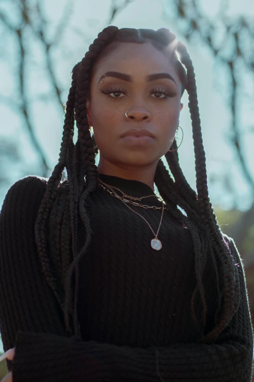 a woman with dreadlocks standing in front of a tree, an album cover, trending on pexels, renaissance, long black braids, aida muluneh, serious look, official screenshot