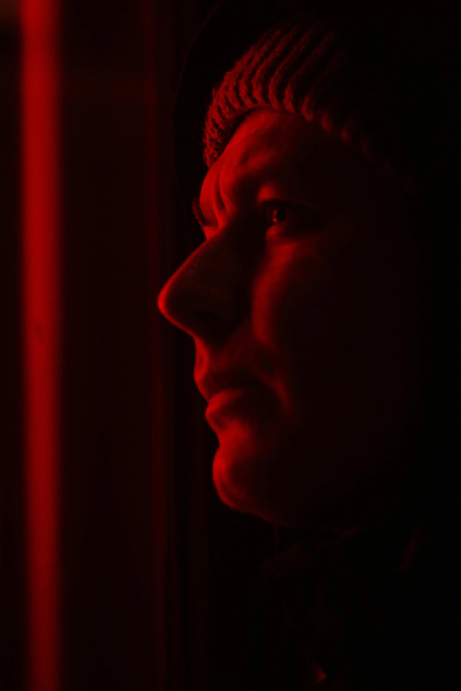 a man standing in front of a red light, profile image, imax close-up of face, jakub rebelka, looking out a window