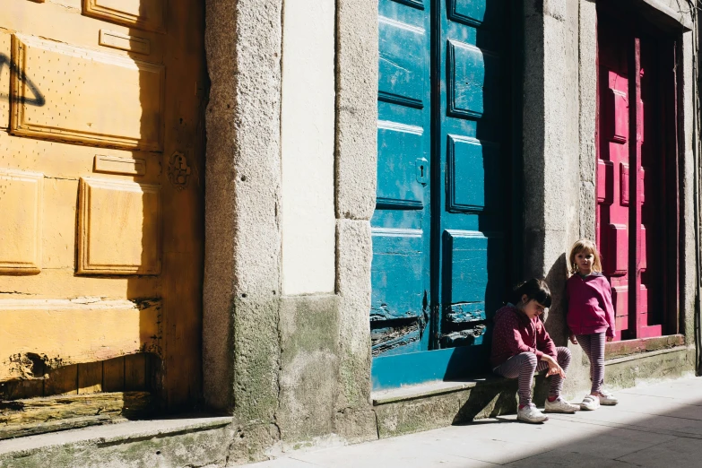 a couple of little girls standing in front of a building, pexels contest winner, arte povera, blue door, shady alleys, 1 7 8 0, complementary colors