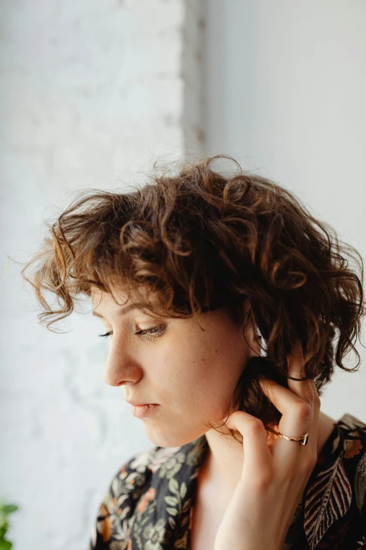 a woman holding a cell phone to her ear, an album cover, inspired by Josefina Tanganelli Plana, trending on pexels, curly bangs, profile image, messy brown short hair, portrait mode photo