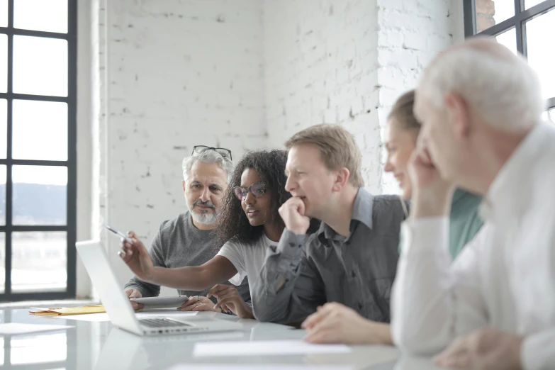 a group of people sitting around a table with a laptop, profile image, grey, teaching, multiple stories