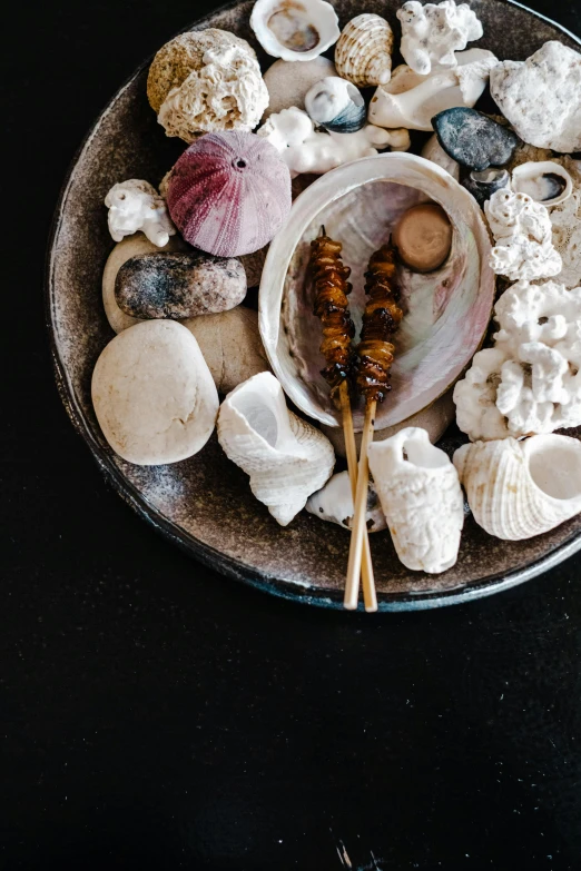 a close up of a plate of food on a table, a still life, unsplash, baroque, shells and barnacles, chopsticks, thumbnail, black