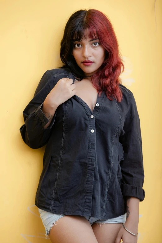 a woman standing in front of a yellow wall, by Max Dauthendey, trending on pexels, messy black / red hair, young himalayan woman, casual black clothing, on grey background