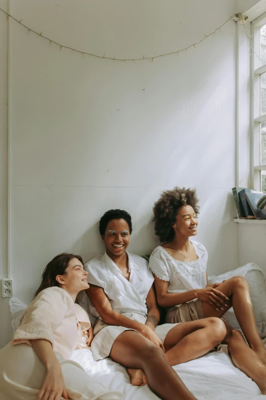 a group of women sitting on top of a bed, by Lily Delissa Joseph, pexels contest winner, smiling softly, but minimalist, three women, ashteroth