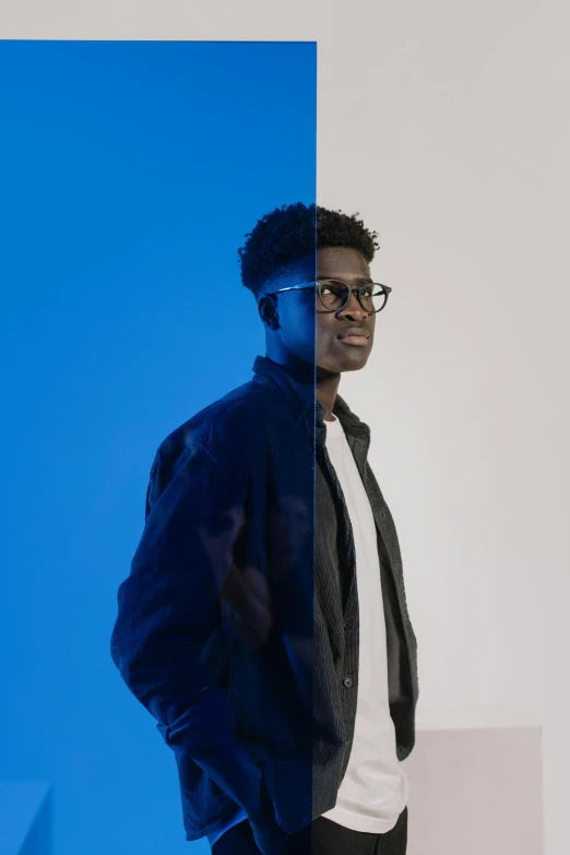 a man standing in front of a blue wall, an album cover, black main color, half and half, man with glasses, light and dark