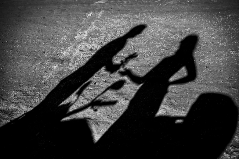 a man riding a skateboard down a street next to a woman, a black and white photo, by Gusztáv Kelety, pexels contest winner, realism, cast shadows, dark figurings, an abstract, consist of shadow