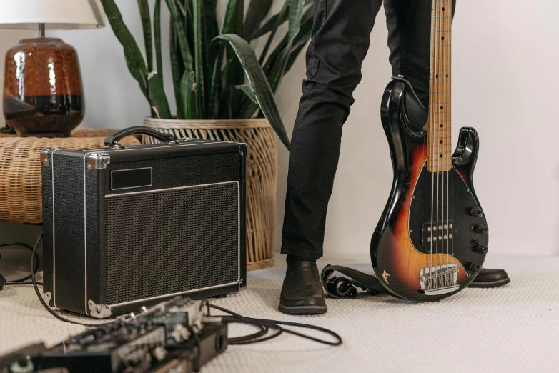 a man standing next to a guitar and amplifier, trending on pexels, bass sound waves on circuitry, australian, detailed product image, 3 band lineup
