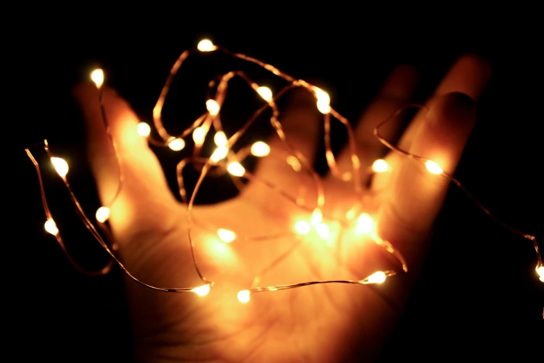 a person holding a string of lights in their hand, gold dappled lighting, instagram photo, screensaver, light tan