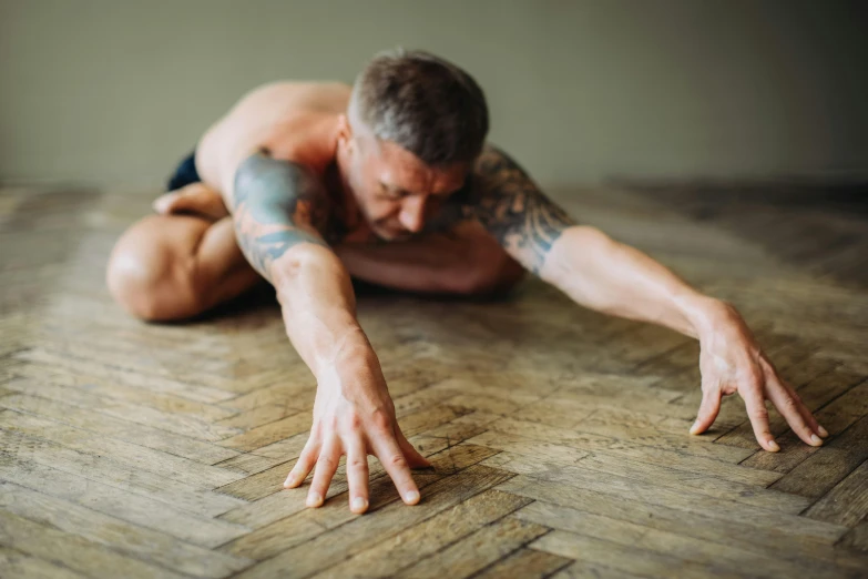 a man doing a yoga pose on the floor, pexels contest winner, renaissance, photograph of a sleeve tattoo, swollen muscles, heroic shooting bow pose, lean man with light tan skin