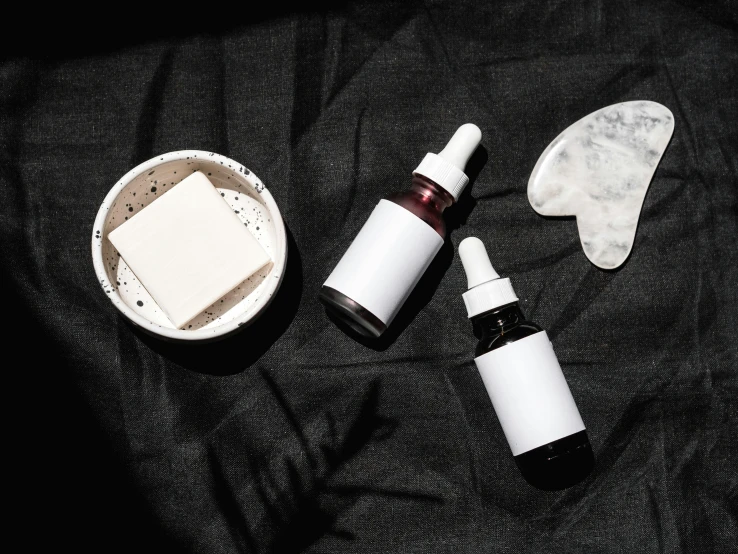 a couple of bottles sitting on top of a table, by Julia Pishtar, trending on pexels, minimalism, white powder makeup, moonless night, medical labels, black oil