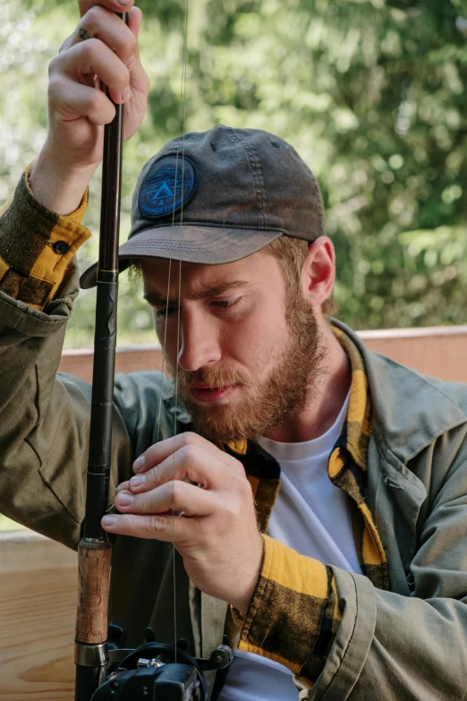 a man sitting on a bench holding a fishing rod, lumberjack flannel, waxed beard, carefully crafted, hand holding cap brim