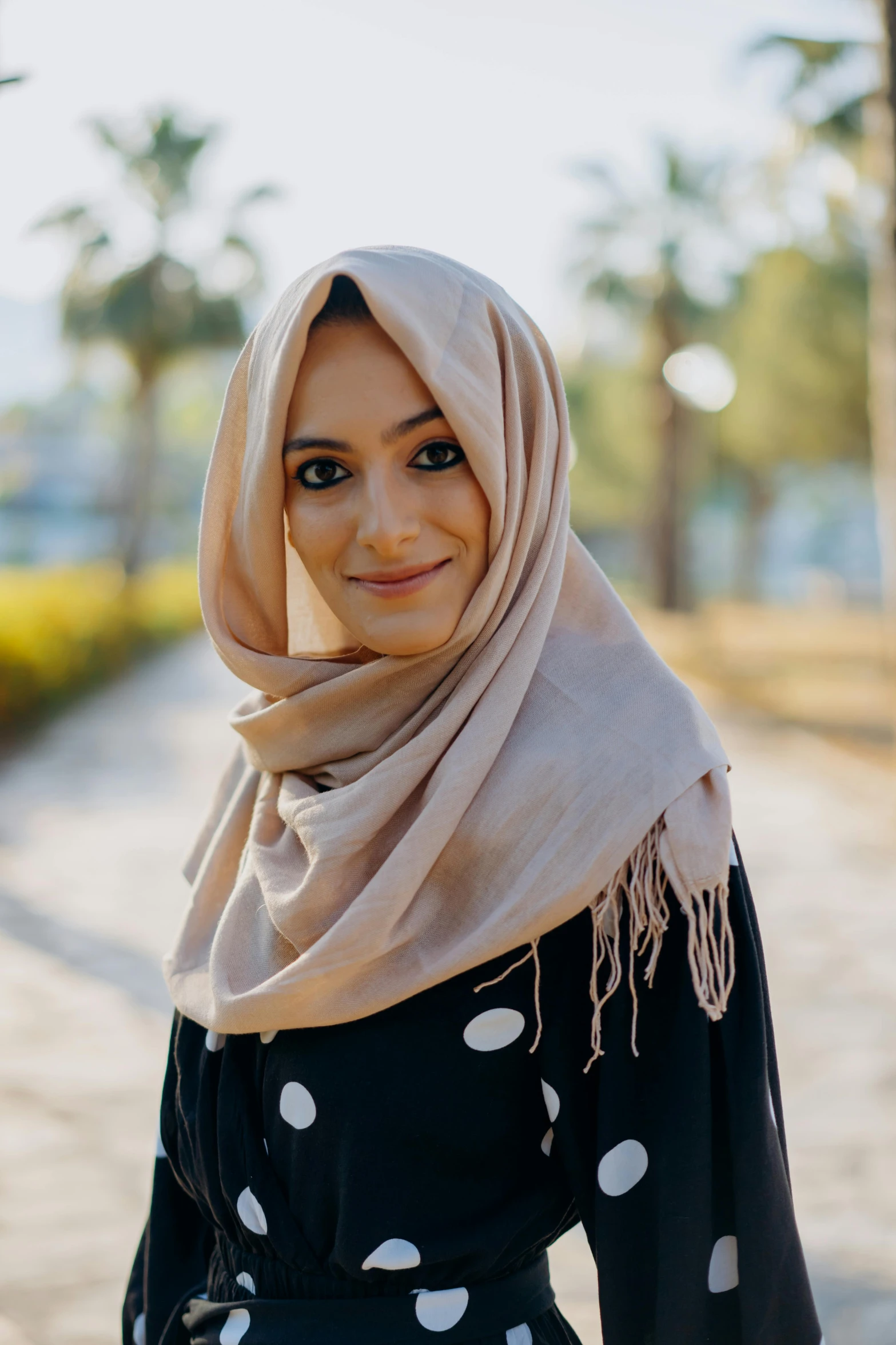 a woman wearing a black and white polka dot dress, inspired by Maryam Hashemi, pexels contest winner, hurufiyya, patterned scarf, beige, malaysian, light tan