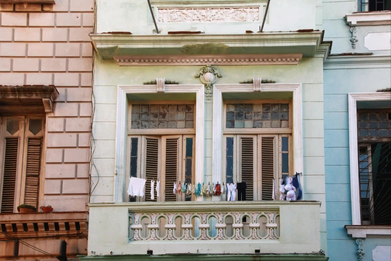 a couple of windows sitting on the side of a building, a colorized photo, by Gina Pellón, pexels contest winner, cuban revolution, decorated with opera motifs, sea - green and white clothes, wes anderson)