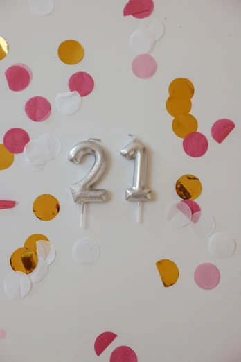 a clock with the number twenty on it surrounded by confetti, by Pamela Drew, unsplash, white candles dripping wax, foil effect, balloon, 21 years old