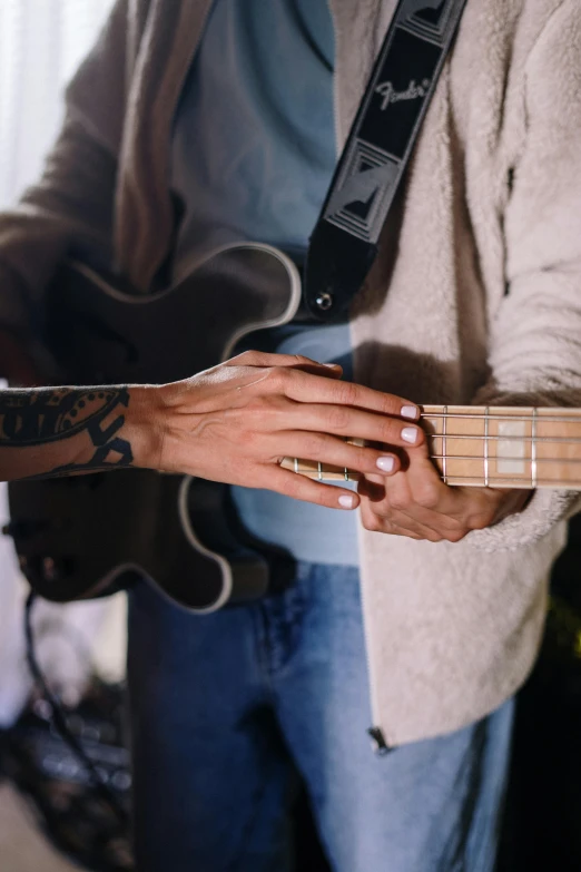 a close up of a person playing a guitar, a tattoo, trending on pexels, antipodeans, holding hands, bassist, wearing presidential band, woman