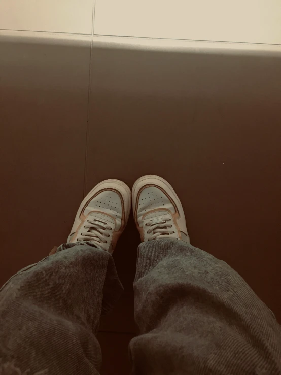 a person standing in a bathroom with their feet on the floor, an album cover, inspired by Elsa Bleda, hyperrealism, blue jeans and grey sneakers, 😭 🤧 💔, sitting in a waiting room, sepia toned
