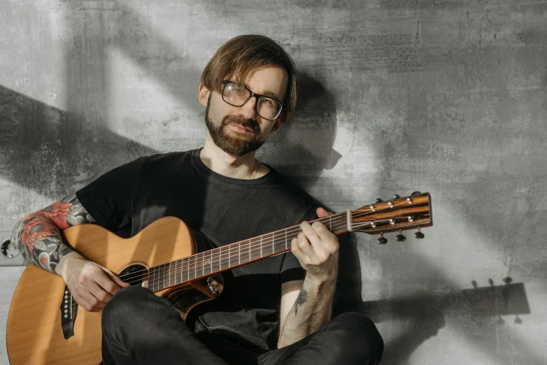 a man sitting on the ground with a guitar, inspired by Serhii Vasylkivsky, shutterstock, with a small beard, on a pale background, holding guitars, david bates