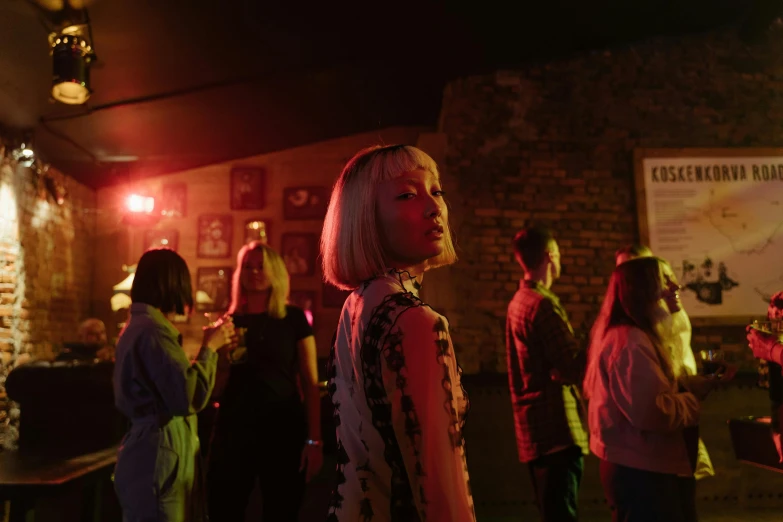 a group of people standing around in a room, an album cover, trending on pexels, realism, night club, portrait a woman like reol, film scene, performing a music video