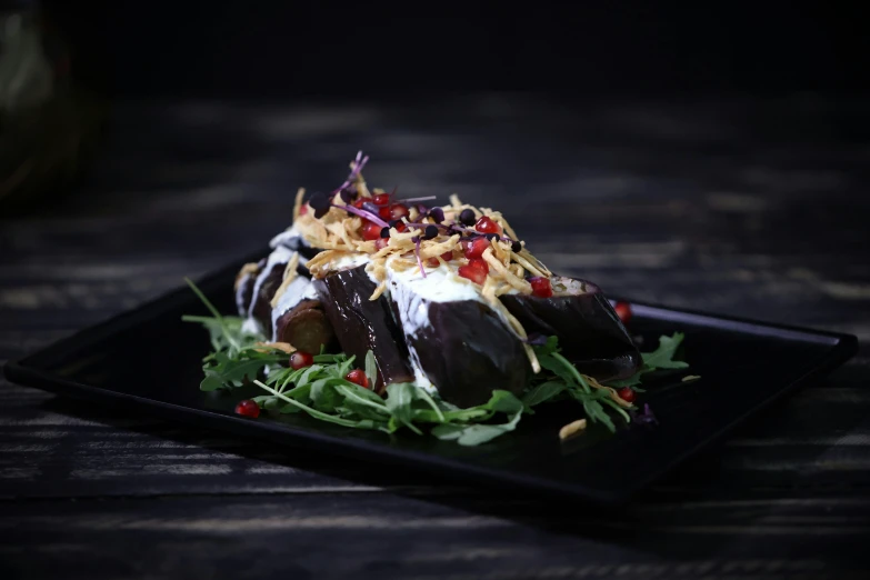 a close up of a plate of food on a table, eggplant, profile image, black, dessert