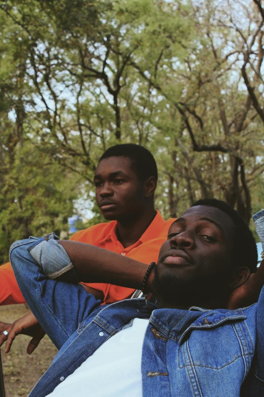 a couple of men sitting next to each other, an album cover, by Stokely Webster, trending on unsplash, visual art, sitting in a tree, brown skinned, looking off into the distance, laying down