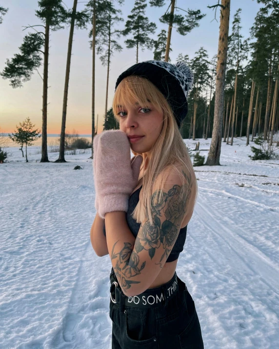 a woman standing in the snow holding a mitt, inspired by Louisa Matthíasdóttir, trending on pexels, with tattoos, better known as amouranth, cottagecore!! fitness body, 90's photo