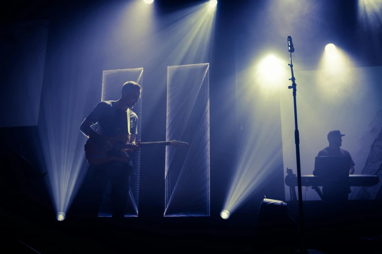a man that is standing on a stage with a guitar, pexels contest winner, light and space, hammershøi, blur : - 2, theatrical lighting, side profile artwork