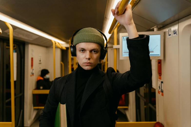 a man wearing headphones on a subway train, pexels, graffiti, holding a wooden staff, wearing a turtleneck and jacket, yulia nevskaya, thumbnail