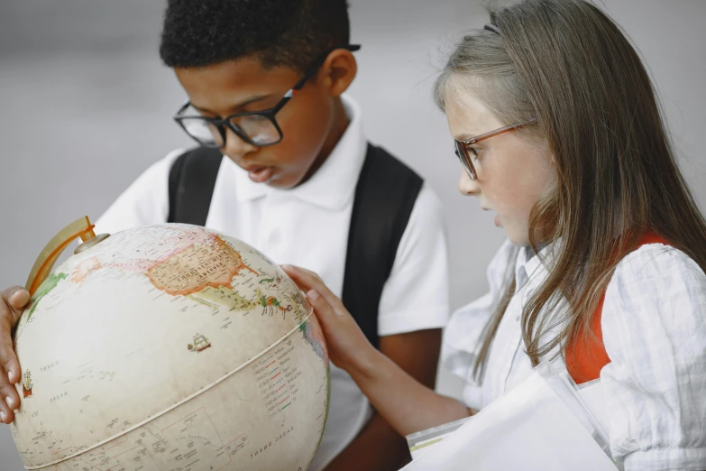 a boy and a girl looking at a globe, pexels, quito school, wearing a school uniform, mix of ethnicities and genders, grey, girl wearing round glasses