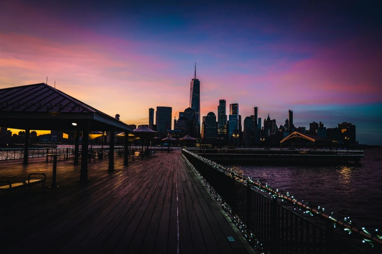 a pier next to a body of water with a city in the background, pexels contest winner, twilight skyline, new york background, multicoloured, high quality image”