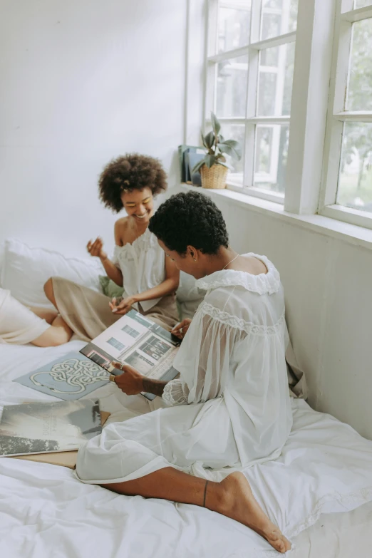 a couple of people that are sitting on a bed, pexels contest winner, magazine sales, kids playing, muted palette mostly white, young women