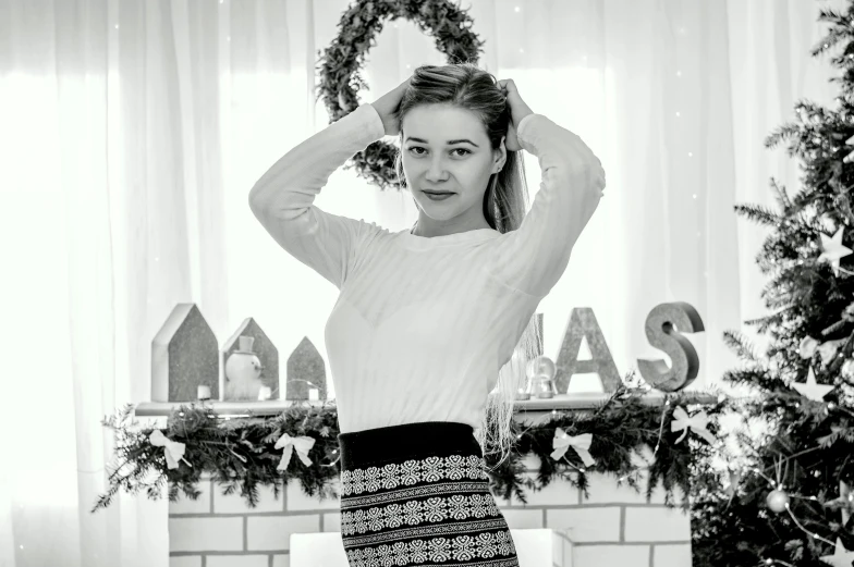 a woman standing in front of a christmas tree, a black and white photo, by Emma Andijewska, pexels contest winner, realism, hailee steinfeld, white russian clothes, cutest, a blond
