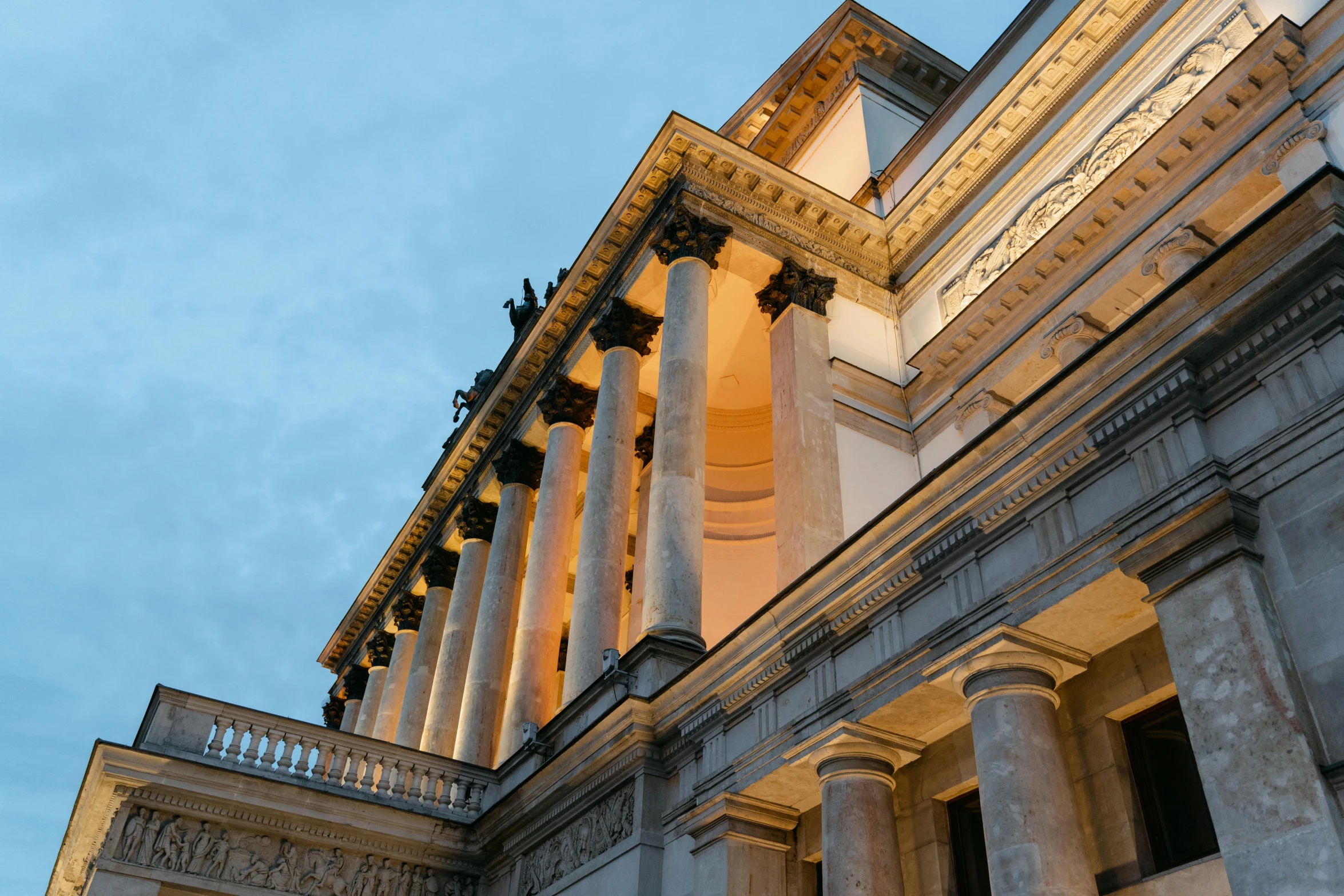 a clock that is on the side of a building, inspired by David Chipperfield, unsplash, neoclassicism, evening lighting, giant columns palace, tall terrace, view from ground level