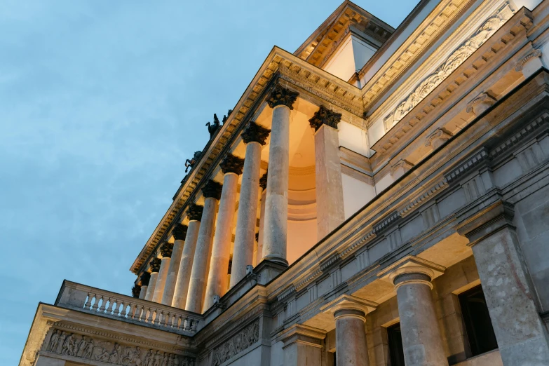 a clock that is on the side of a building, inspired by David Chipperfield, unsplash, neoclassicism, evening lighting, giant columns palace, tall terrace, view from ground level