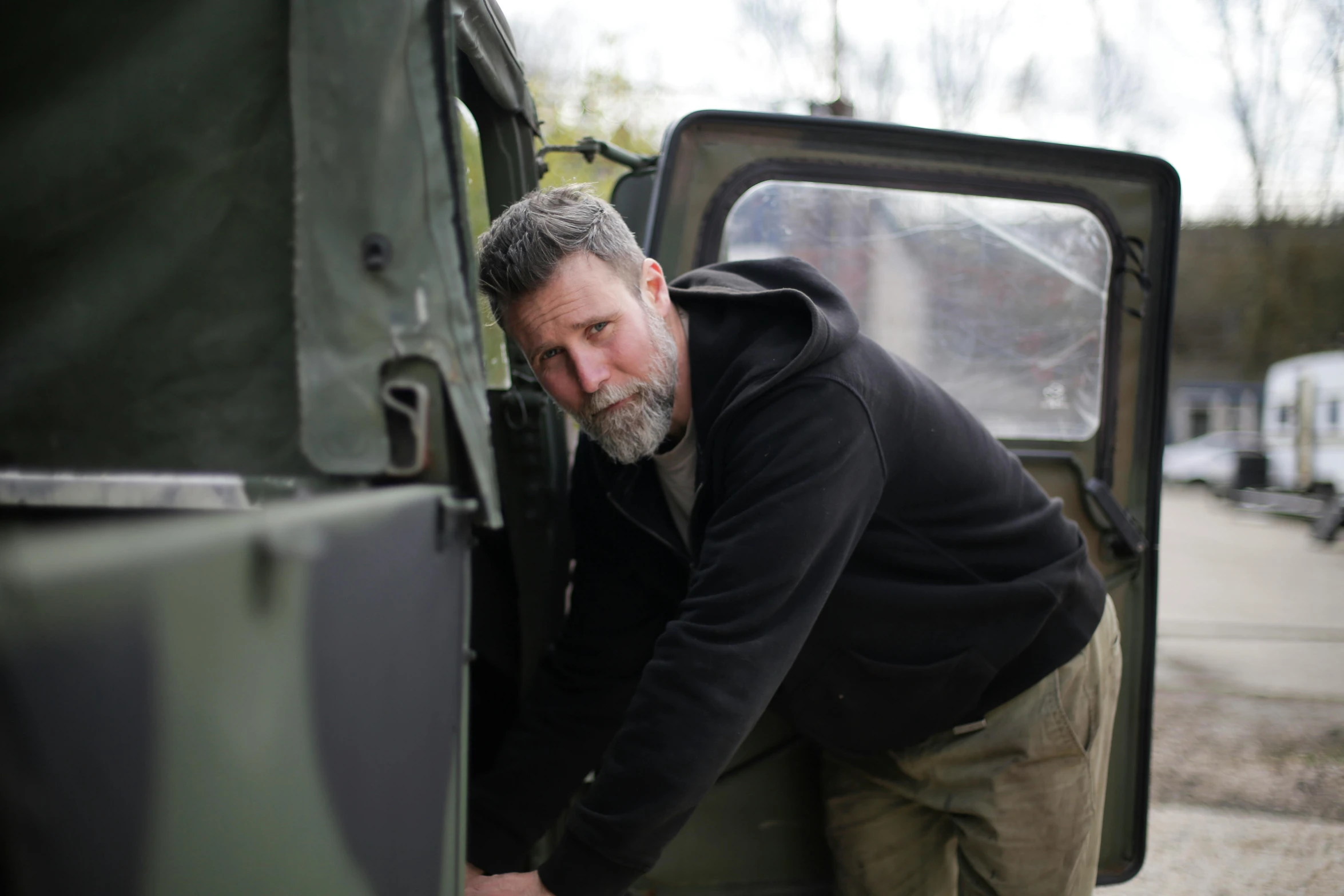 a man leaning on the door of a military vehicle, a portrait, unsplash, photorealism, aiden gillen, digging, bearded and built, gordon onslow ford