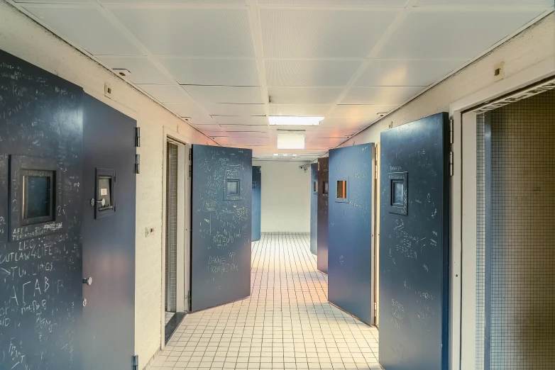 a hallway with blue doors and writing on the walls, unsplash, private press, stood in a cell, suspended ceiling, investigation, thumbnail