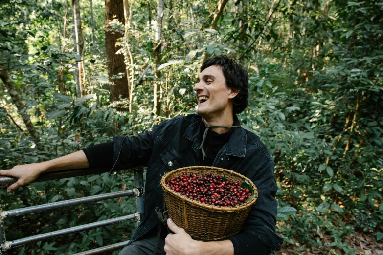 a man sitting on a bench holding a basket of cherries, in the jungle, aussie baristas, profile image