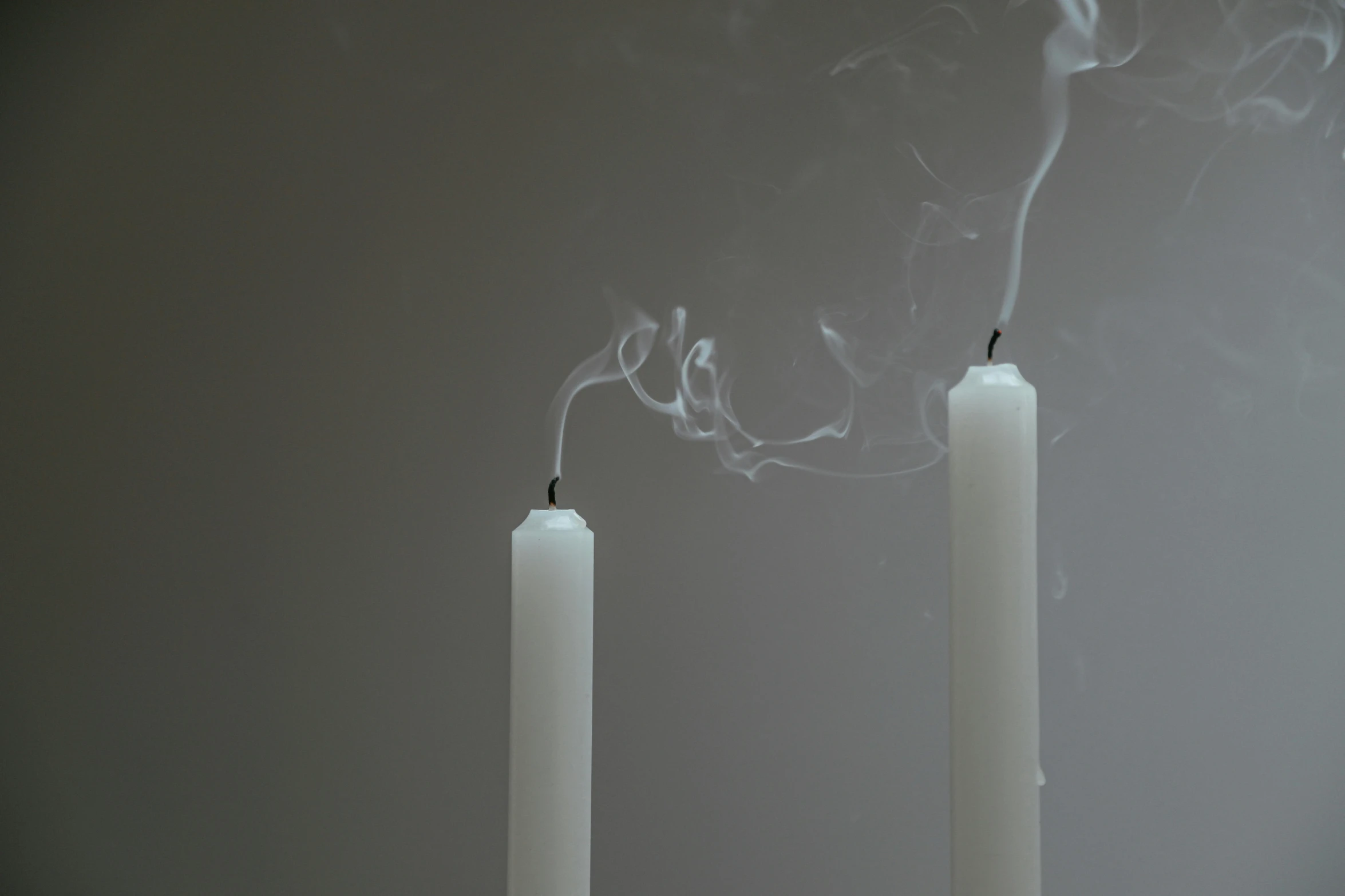 a couple of white candles sitting on top of a table, an album cover, inspired by Robert Mapplethorpe, unsplash, smoke tendrils, light grey mist, mid shot, videogame still