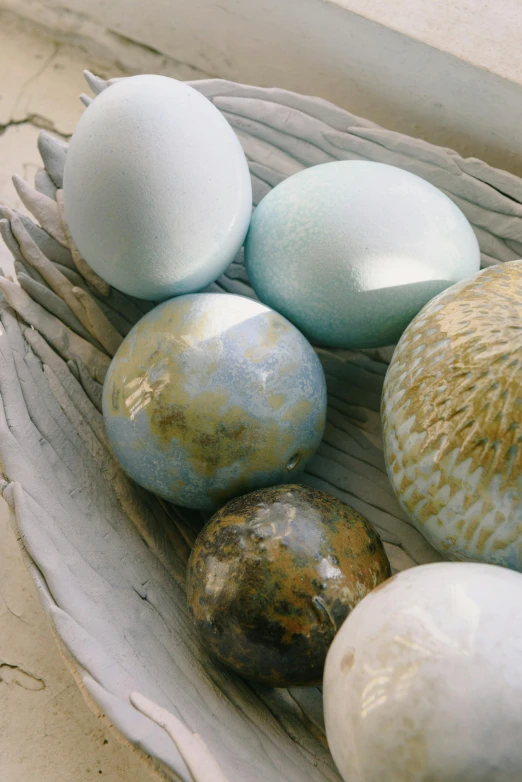 a bowl filled with eggs sitting on top of a table, a marble sculpture, by Jessie Algie, glistening seafoam, five planets, soft-sanded coastlines, up close