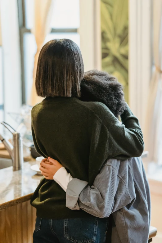 two women hugging each other in a kitchen, pexels, black haired girl wearing hoodie, mourning family, with his back turned, customers