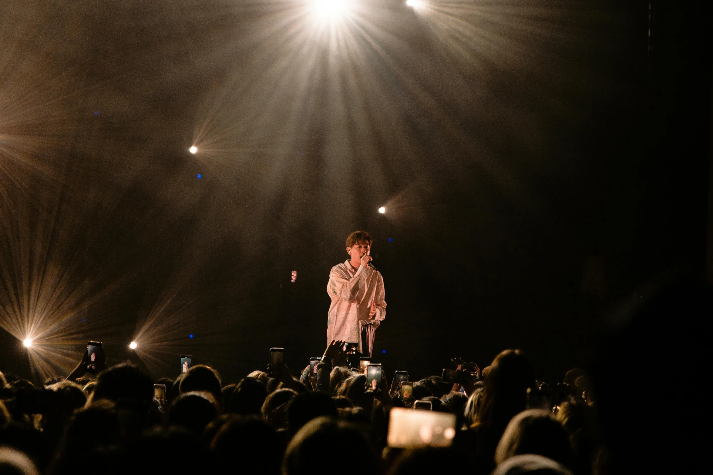 a man standing on top of a stage in front of a crowd, an album cover, unsplash, happening, jungkook, bo burnham, lowkey lighting, full faced