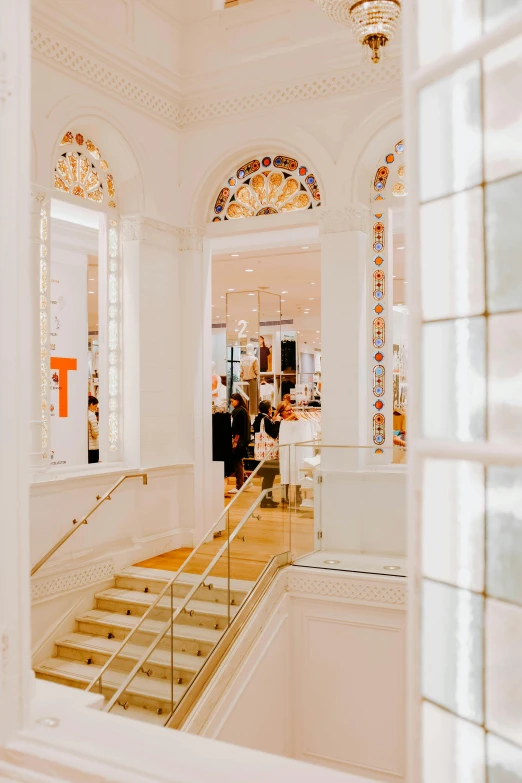 a view of the inside of a building through a window, a digital rendering, trending on unsplash, art nouveau, white and orange, people shopping, wide grand staircase, victoria's secret