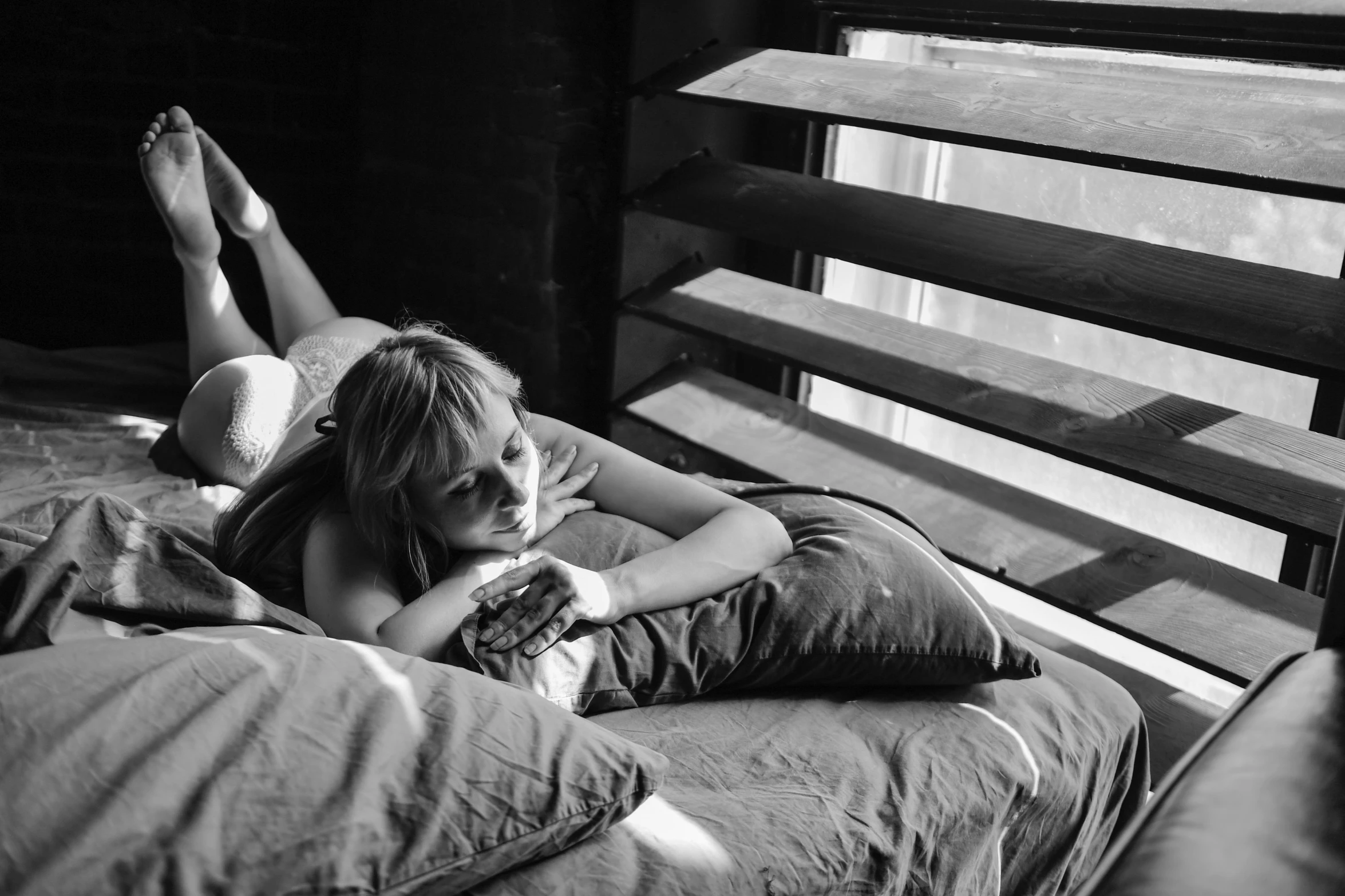 a woman laying on top of a bed next to a window, inspired by Nan Goldin, visual art, bw photo, imogen poots, couple on bed, picture of a loft in morning