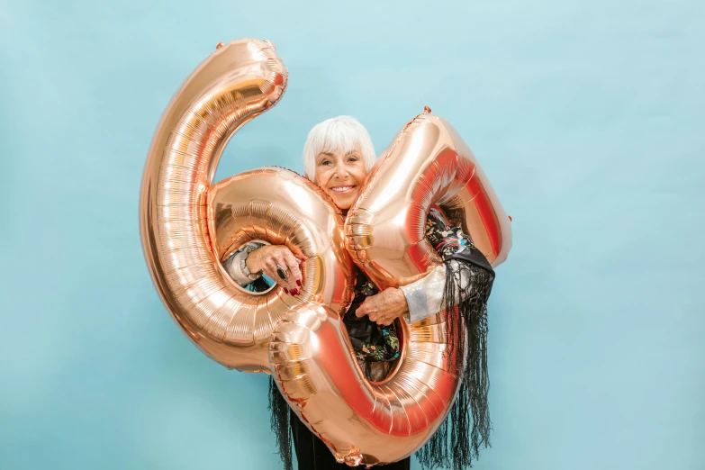 a woman holding a large gold number balloon, by Julia Pishtar, pexels contest winner, elderly, six arms, happy birthday, - 6