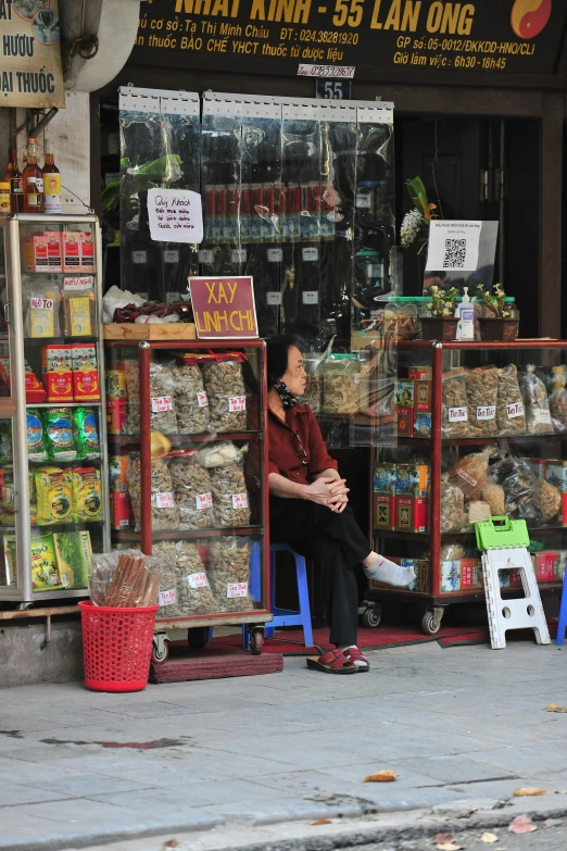 a woman sitting on a bench in front of a store, inspired by Cui Bai, pexels contest winner, dried herbs, cigars, old cmputers on the sidewalk, img _ 9 7 5. raw