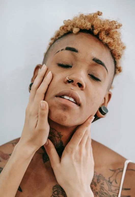 a close up of a person touching their face, a tattoo, by Dulah Marie Evans, ashteroth, skin care, waking up, androgyny