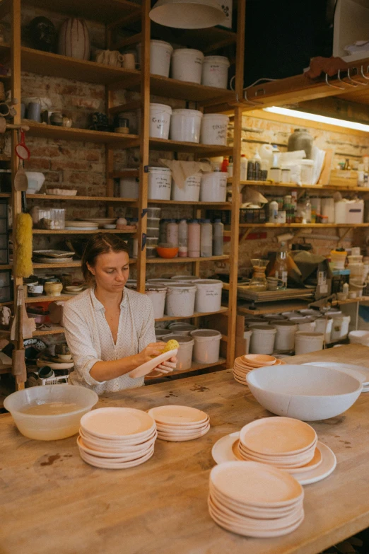 a woman sitting at a table with bowls and plates, process art, big production, australian, quality, cast