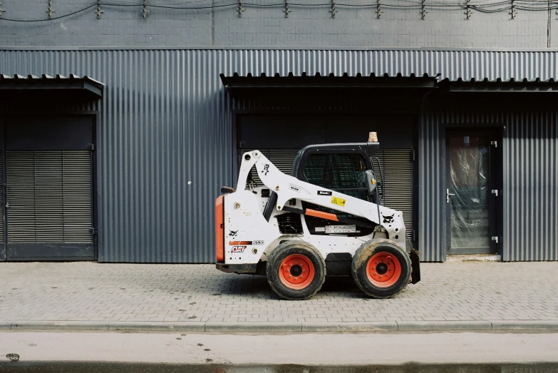 a small ski - loader parked in front of a building, unsplash, arbeitsrat für kunst, heavy machinery, white panels, white buildings with red roofs, farming