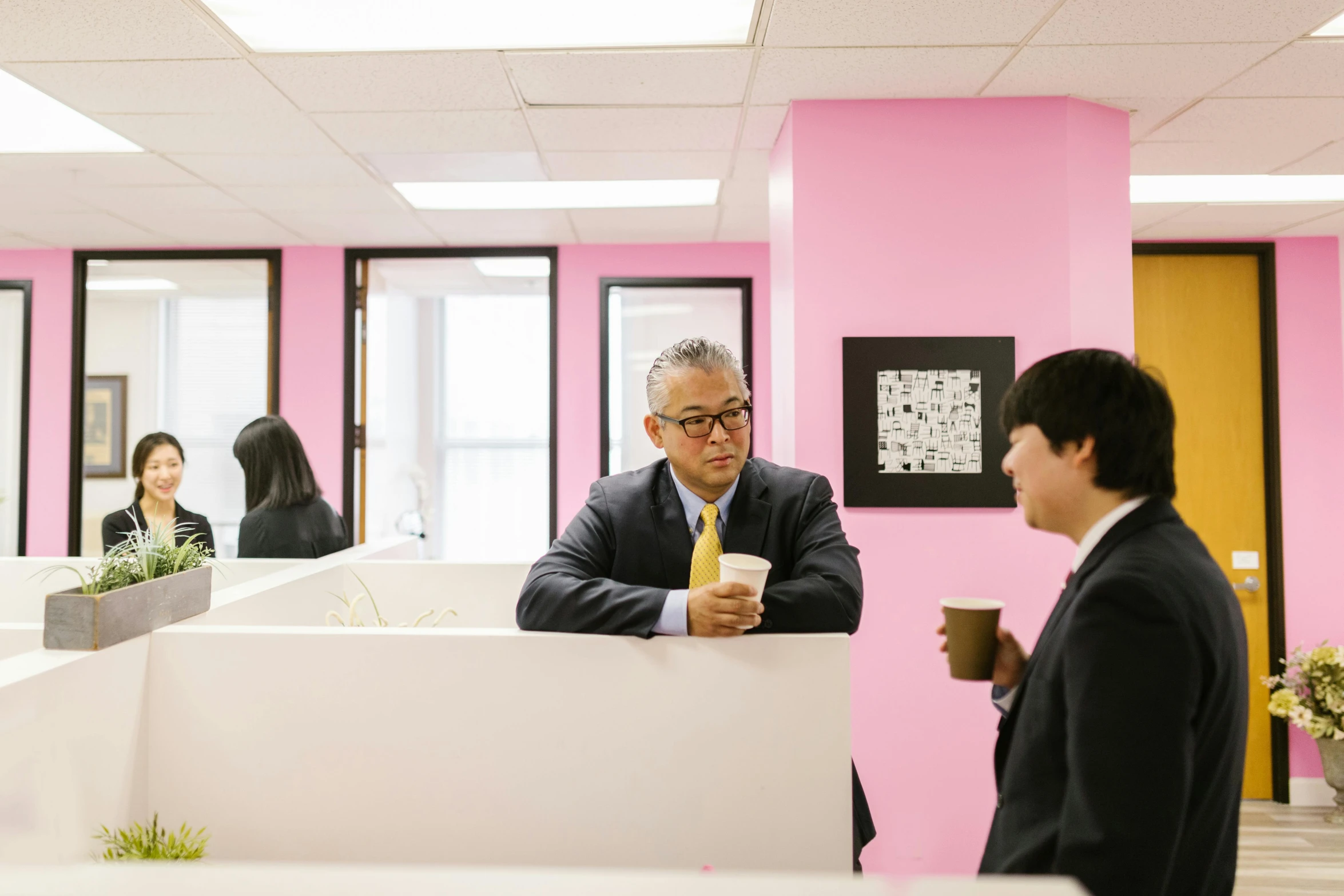 a couple of men standing next to each other in an office, a photo, inspired by Yokoyama Taikan, unsplash, shin hanga, brightly lit pink room, person in foreground, wearing a suit and glasses, people at work